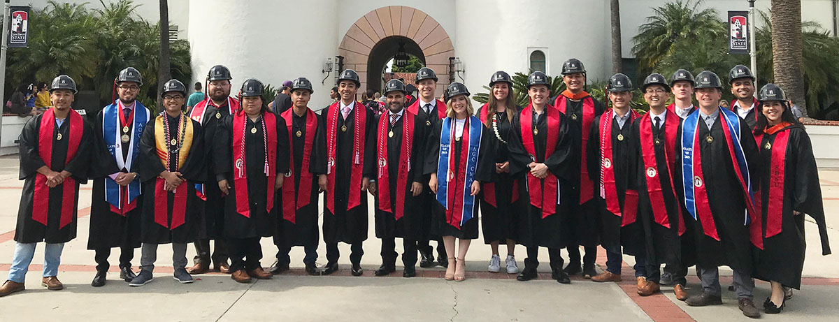 A group of CCEE graduates in cap and gown, in front of Hepner Hall.